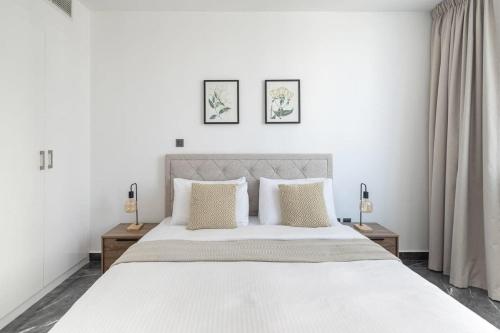 a white bedroom with a large white bed with two tables at Frank Porter - Burj Al Nujoom in Dubai