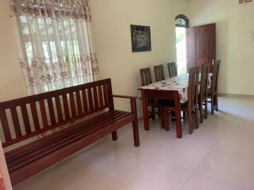 ein Esszimmer mit einem Tisch und Holzbänken in der Unterkunft Cinnamon Villa AMBA in Ambalangoda