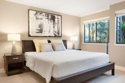 a bedroom with a bed with two lamps and two windows at 115 Modern and Serene Min to Downtown in Bellevue