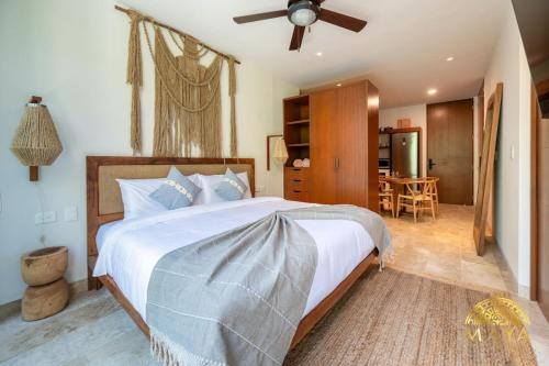 a bedroom with a large bed with a ceiling fan at NHOA 206B Lux 1BR Condo Jungle View in Aldea Zama in Tulum