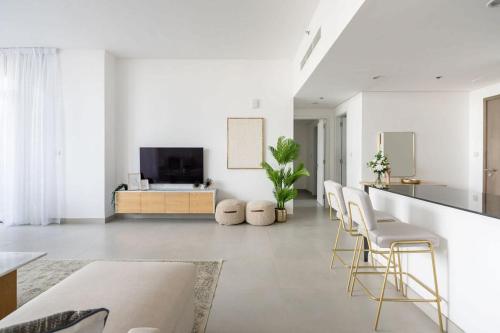 a living room with white walls and a bar with stools at Frank Porter - Pulse C2 in Dubai