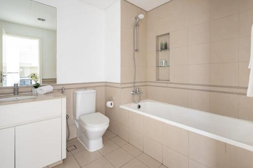 a bathroom with a toilet and a tub and a sink at Frank Porter - Hayat Boulevard 1A in Dubai
