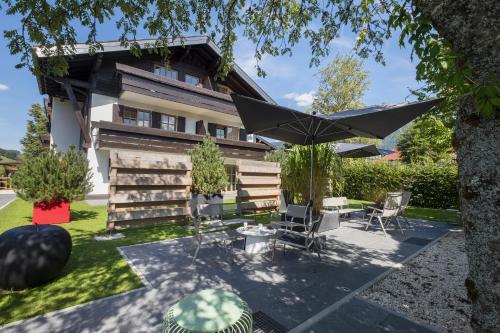 eine Terrasse mit einem Sonnenschirm und Stühlen vor einem Haus in der Unterkunft Boutique Hotel Gams in Oberstdorf