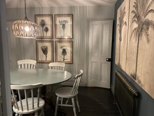 ein Esszimmer mit einem Tisch und weißen Stühlen in der Unterkunft Charming Bight Cottage moments from beach by Whitstable-Holidays in Whitstable