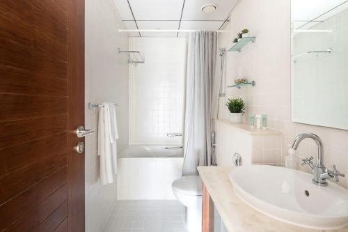 a bathroom with a sink and a toilet and a tub at Frank Porter - Al Sahab 2 in Dubai
