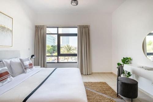 a white bedroom with a large bed and a window at Frank Porter - Al Sidir 2 in Dubai