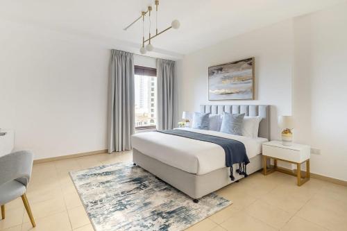 a white bedroom with a large bed and a window at Frank Porter - Murjan 1 in Dubai