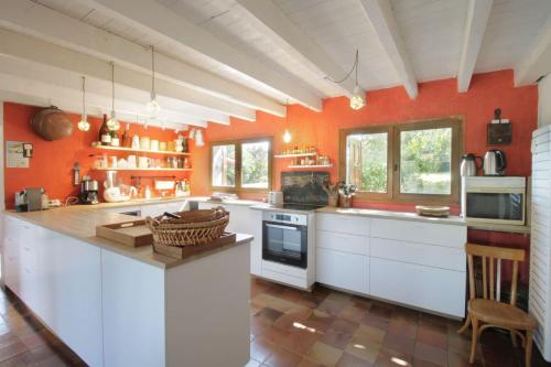 uma grande cozinha com paredes cor de laranja e armários brancos em Comfortable family chalet 5 min drive from the lake em Viviers-du-Lac