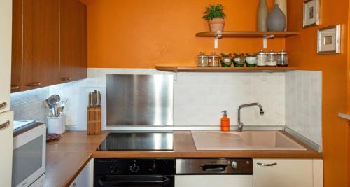a kitchen with a sink and an orange wall at Dimora Altana in Brescia