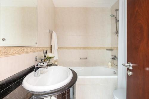 a white bathroom with a sink and a bath tub at Frank Porter - Elite Residence in Dubai