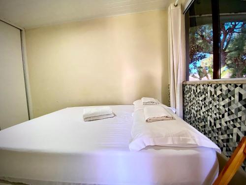 a white bed in a room with a window at Casinha da Praia in Aracaju