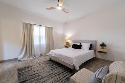 ein weißes Schlafzimmer mit einem Bett und einem Deckenventilator in der Unterkunft SōLE 2BD 2BTH-Condo 3 in Cocoa Beach