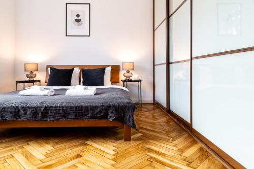 um quarto com uma cama e piso em madeira em Househost Apartment: Józefa 2/10 em Cracóvia