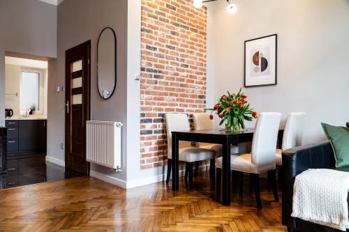 uma sala de jantar com uma mesa e uma parede de tijolos em Househost Apartment: Józefa 2/10 em Cracóvia