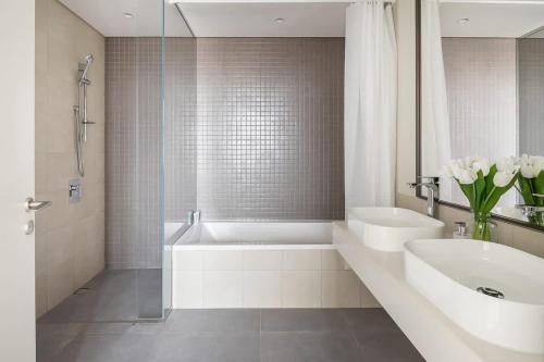 a white bathroom with a tub and a sink and a bath tubermott at Frank Porter - 1 Residences 2 East Tower in Dubai