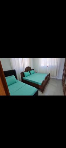 - 2 lits dans une petite chambre avec des draps verts dans l'établissement Apartament Cornerstone, à Shkodër