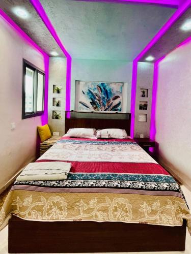a bedroom with a large bed with purple lighting at Appartement au centre d´agadir in Agadir