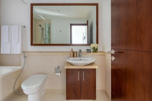 a bathroom with a sink and a toilet and a mirror at Frank Porter - Beauport in Dubai