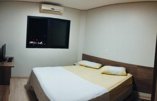 - une chambre avec un lit et une télévision murale dans l'établissement Quarto Centro Dourados, à Dourados