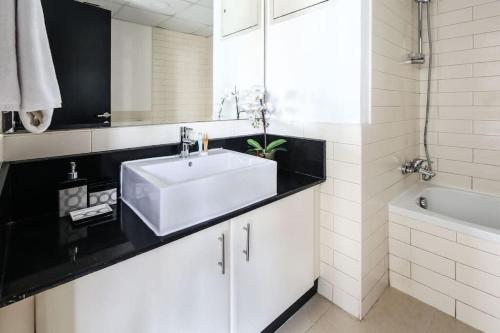 een witte badkamer met een wastafel en een bad bij Frank Porter - Yach Bay in Dubai