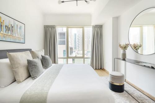 a white bedroom with a large bed and a mirror at Frank Porter - Al Majara in Dubai