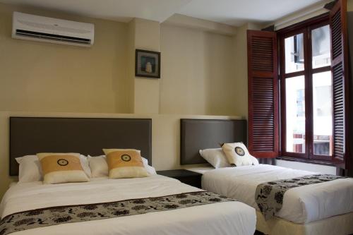 a hotel room with two beds and a window at SohoTown Hotel in Kuala Lumpur
