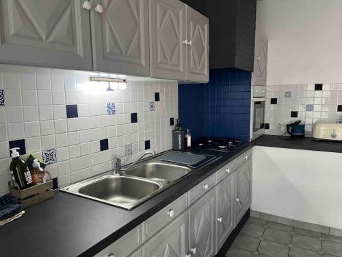 a kitchen with a sink and blue and white tiles at Appartement mezzanine spacieux in Jaunay-Marigny