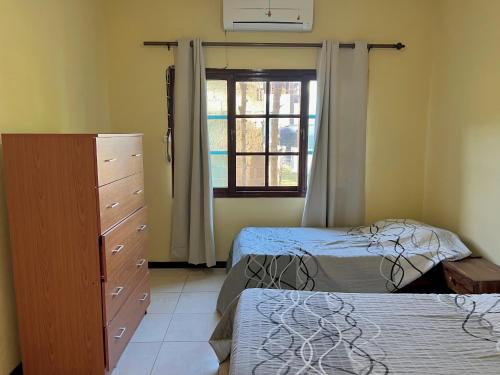 - une chambre avec 2 lits, une commode et une fenêtre dans l'établissement Garden House, à Lopes