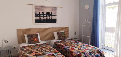 a bedroom with two beds and a cross on the wall at A-Típica GuestHouse in Ponta Delgada