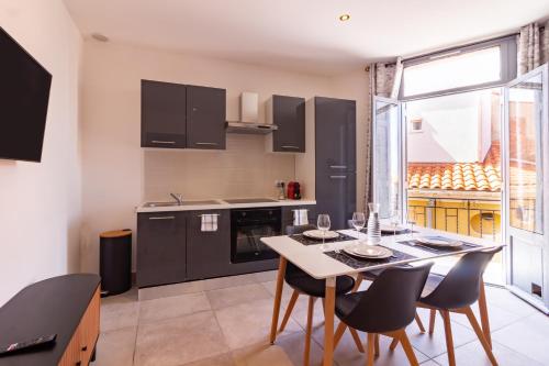 une cuisine avec une table et des chaises et une cuisine avec des armoires noires dans l'établissement Appartement moderne et élégant Michel Torrent, à Perpignan