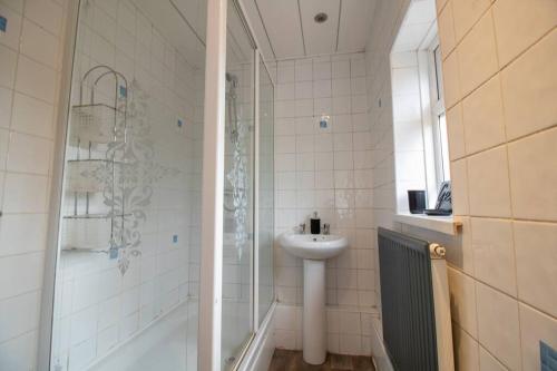 La salle de bains blanche est pourvue d'un lavabo et d'une douche. dans l'établissement K Suites - Lime Grove, à Ryton