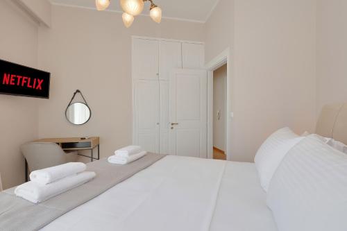 a white bedroom with a large white bed and a table at Olympic Zeus Apartment in Athens
