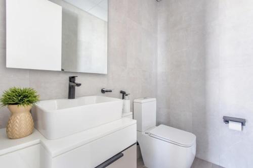 a white bathroom with a sink and a toilet at Frank Porter - Noor 3 Midtown in Dubai