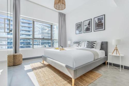 a white bedroom with a large bed and large windows at Frank Porter - Marina Views Tower B in Dubai