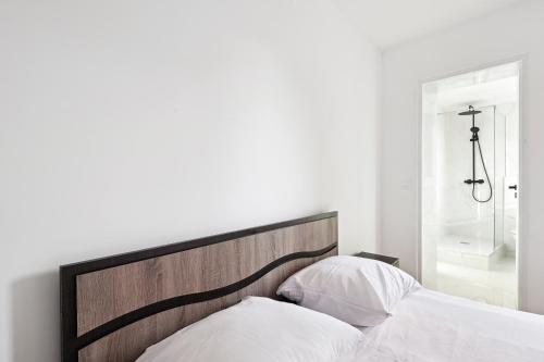 uma cama com uma cabeceira em madeira num quarto em Cozy T2 + Cuisine - cœur d'Arpajon em Arpajon