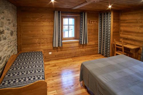 a bedroom in a log cabin with a bed and a window at Chalet du Paradis in Cogne