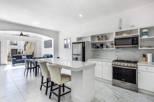 a white kitchen with a table and some chairs at Casa 12 - Playa Arcangel in Rosarito