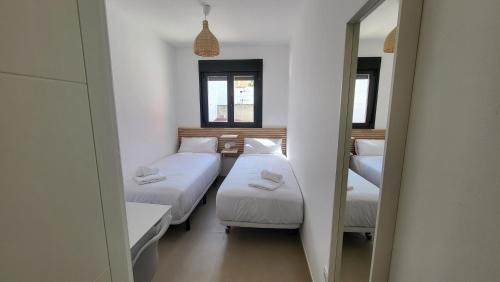 Habitación con 3 camas y espejo. en RentalSevilla La Salle, en Sevilla