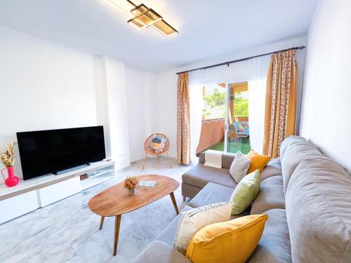 uma sala de estar com um sofá e uma televisão em La Reserva Beach & Golf Apartment em Marbella