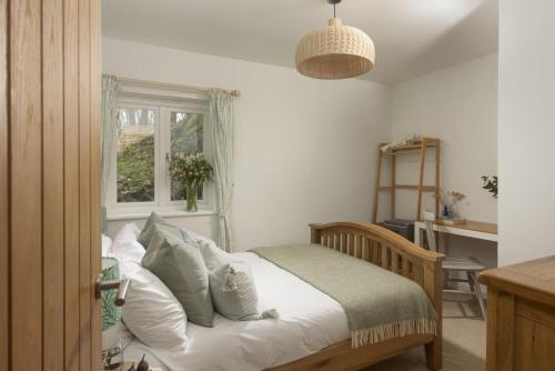 Lobbs Cottage, St Mawgan في Saint Mawgan: غرفة نوم بسرير ومخدات بيضاء ونافذة