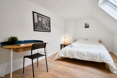 een slaapkamer met een bed en een bureau en een tafel en stoel bij Maison L'Escale Paisible in Anstaing