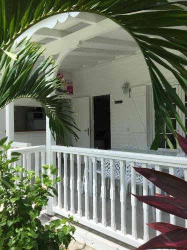 un porche blanco con una barandilla blanca y una palmera en Chambres d'hôtes et villas chez Flo, en Saint-François