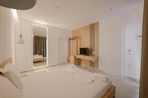 biały pokój z łóżkiem i telewizorem w obiekcie Villa Xhefri w Sarandzie