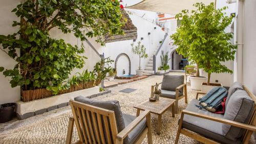 een patio met stoelen, tafels en bomen bij Hostel Casa d'Alagoa in Faro