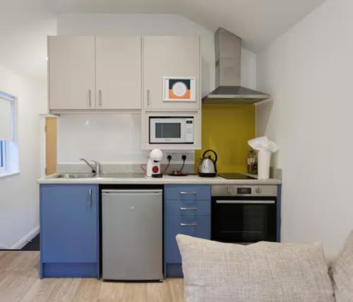 una cucina con armadi blu e bianchi e forno a microonde di Beautiful Studio Apt in Belfast a Belfast