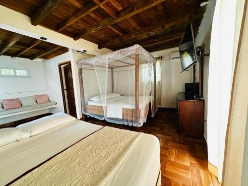 a bedroom with a canopy bed and a television at Casa Pierre in Monterrico