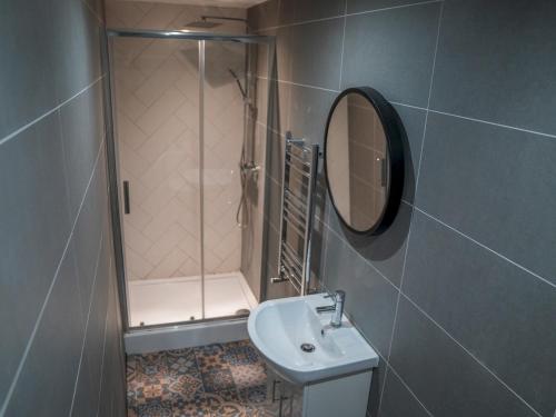 een badkamer met een wastafel, een douche en een spiegel bij Sophisticated private getaway Pass the Keys in Beeston