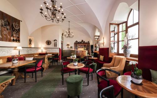 a restaurant with tables and chairs and a chandelier at Classic Hotel Am Stetteneck in Ortisei