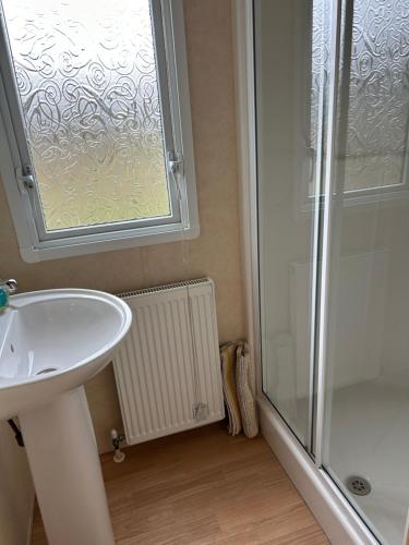 a bathroom with a sink and a shower with a window at Curacao Caravans in Taynuilt