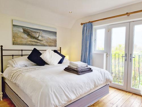 a bedroom with a bed and a large window at Blacksmiths Cottage, Bosham in Bosham